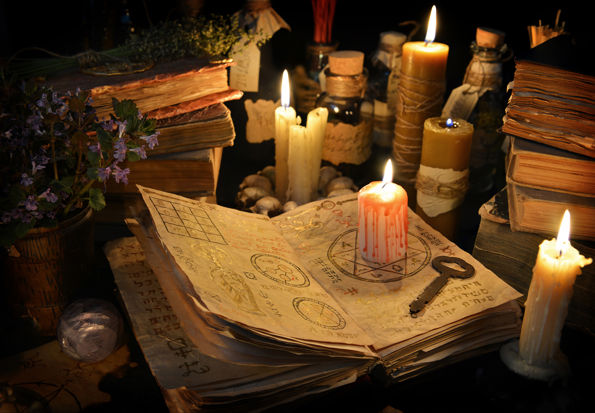 Halloween still life with burning candle on witch book and magic objects in candle light